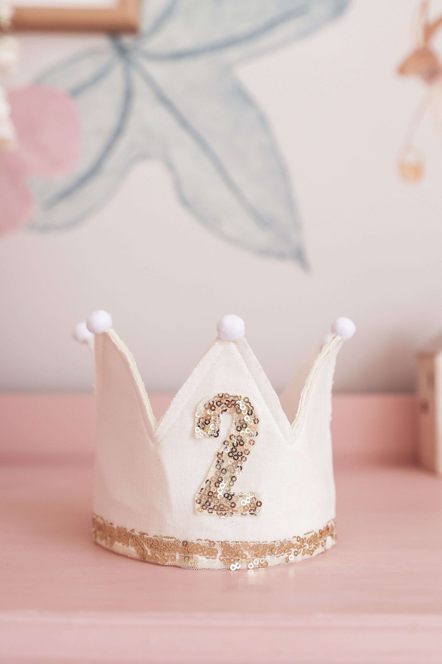 Adjustable ivory linen crown for 2nd birthday, adorned with gold sequins and pom poms, perfect for little celebrations.