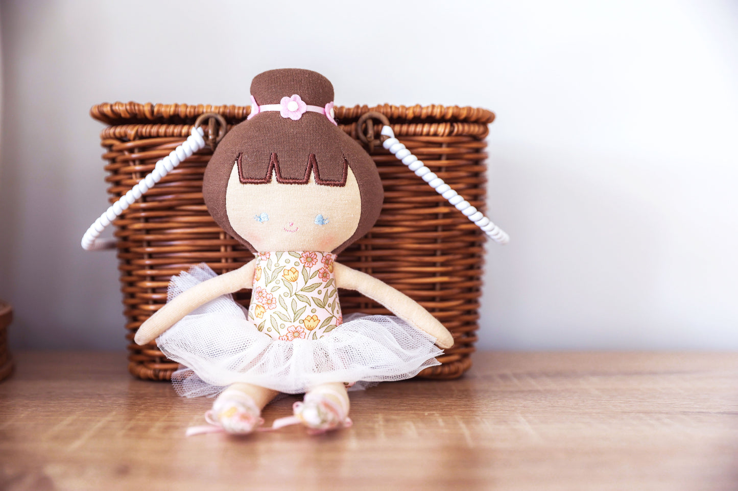 Baby ballerina doll with tulle tutu and floral bodice, 25cm tall, beside a wicker basket, perfect for children from 3 years.