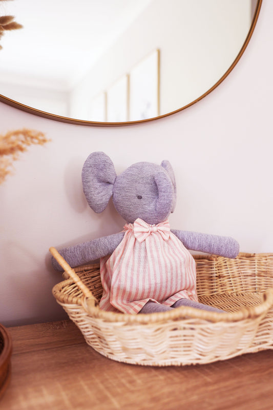 Big Elsie Elephant 40cm in a cute striped dress, handcrafted, sitting in a basket beside a mirror.