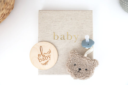 Sherpa bear pacifier comforter in oatmeal color with wooden baby sign, perfect for soothing infants.