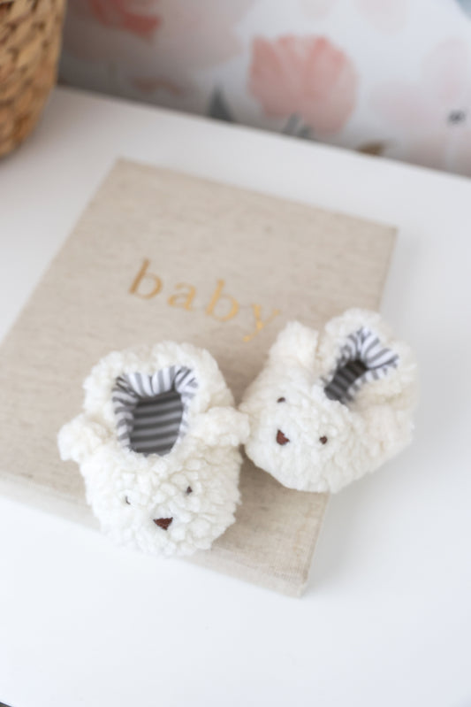 Sherpa bear booties ivory for infants 0-6 months, soft, machine washable, with bear face design, on a baby-themed background.