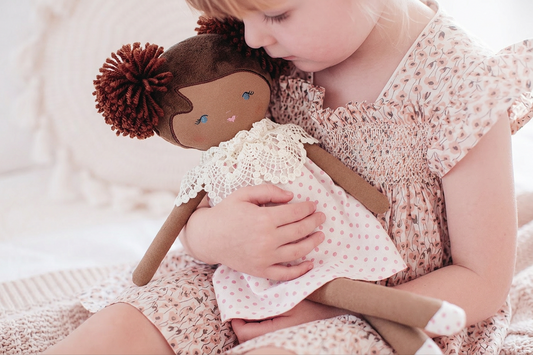 45cm soft fabric doll with dark brown skin, brown yarn hair in pom-poms, white crocheted top, and pink polka dot skirt.