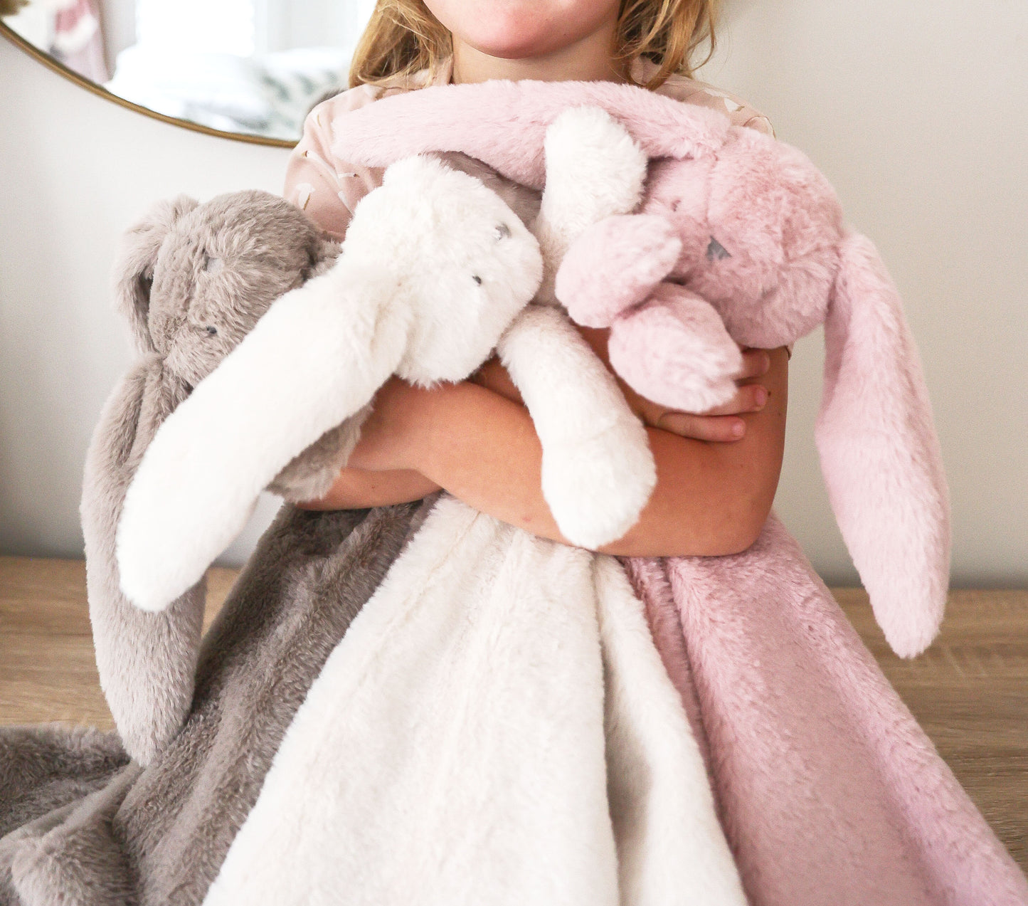Plush ivory blanket with long-eared bunny lovey design held by child, soft textured fabric.
