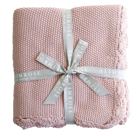 Petal pink knit mini moss stitch baby blanket with scalloped edge, tied with gray Alimrose ribbon.