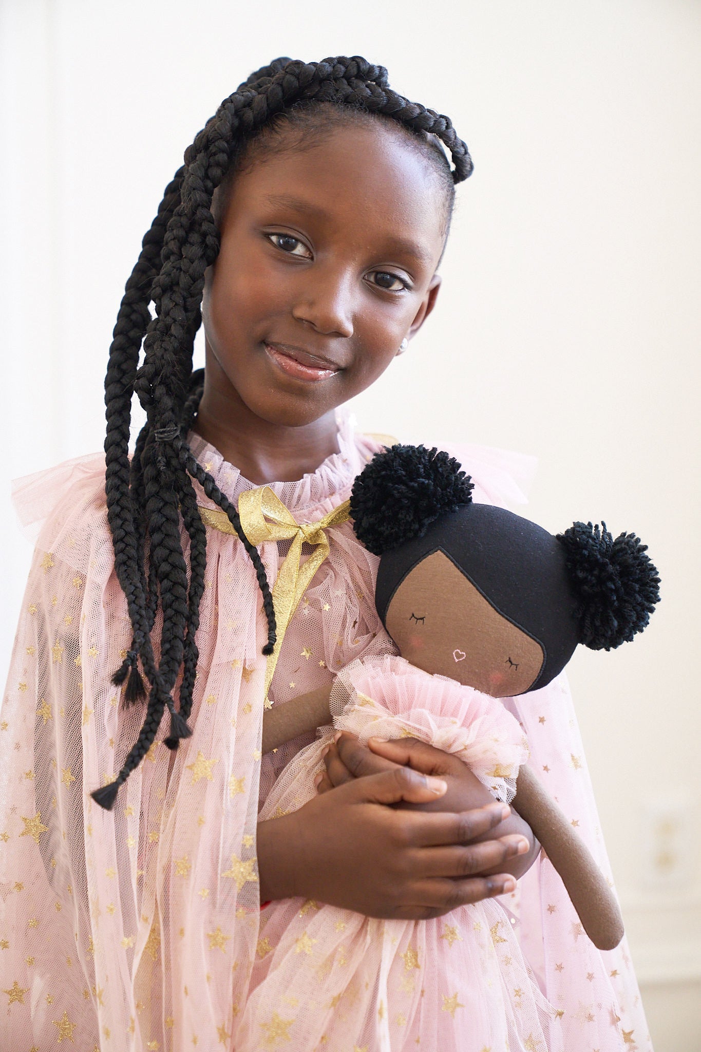 Smiling girl in a pink starry dress holding Alimrose Halle Ballerina Doll, showcasing its whimsical design.