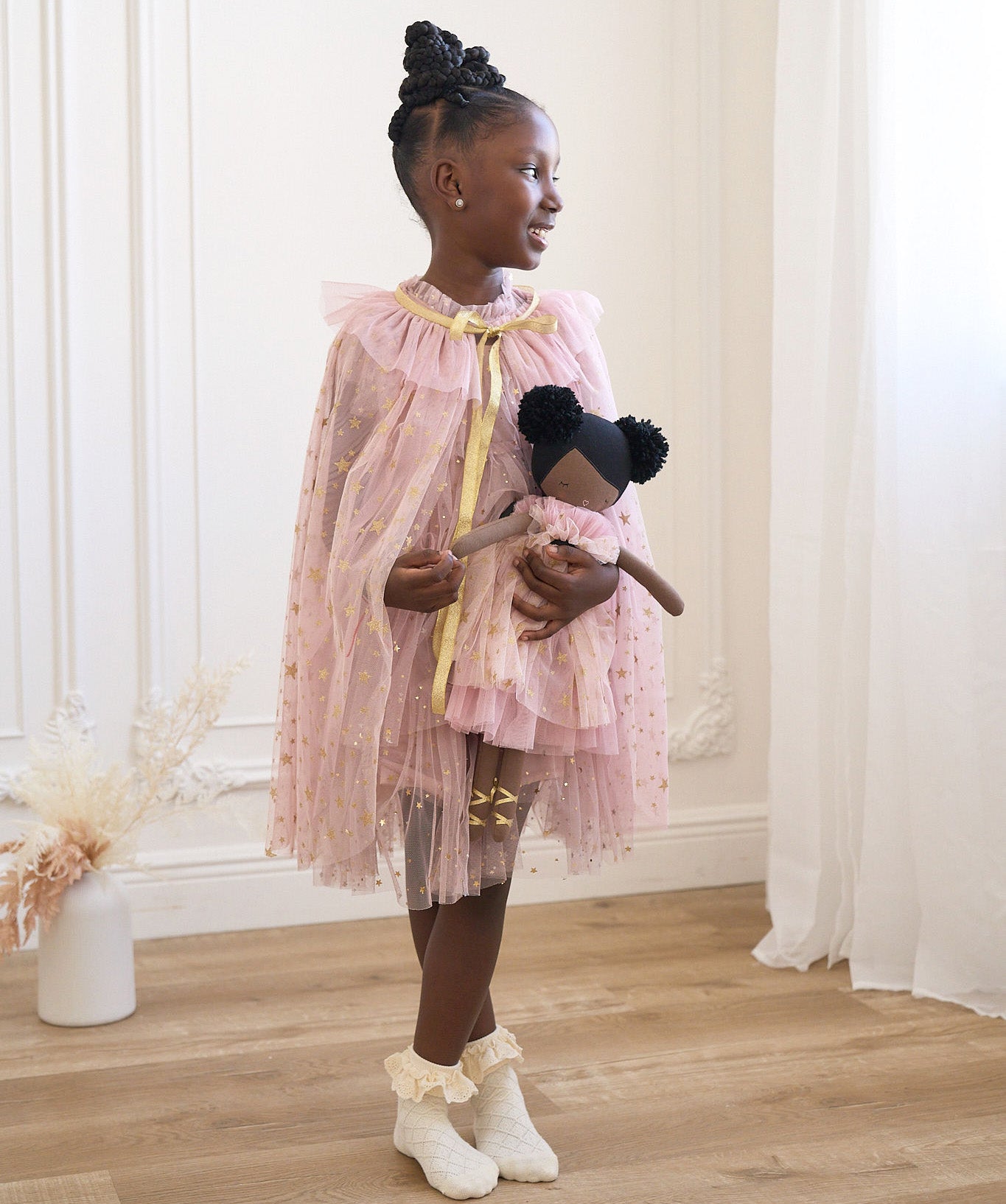 Young girl in pink tulle cape holding Alimrose Halle Ballerina Doll, showcasing playful elegance and creativity.