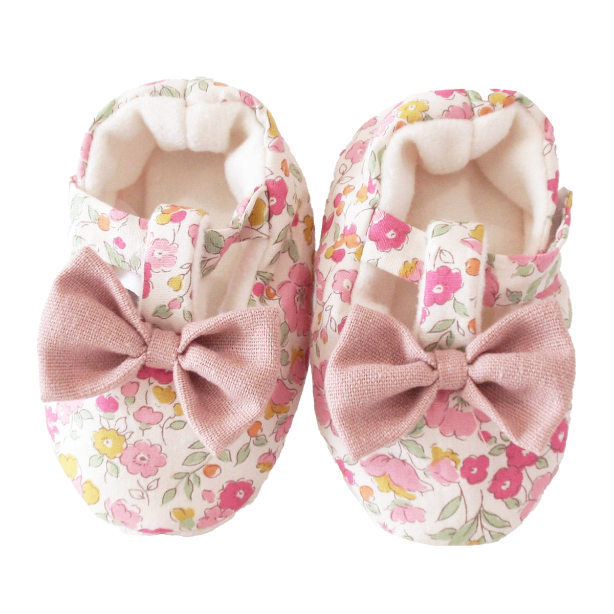 Soft fabric baby booties with pink velvet bows and a floral rose garden print in pink, yellow, and green.
