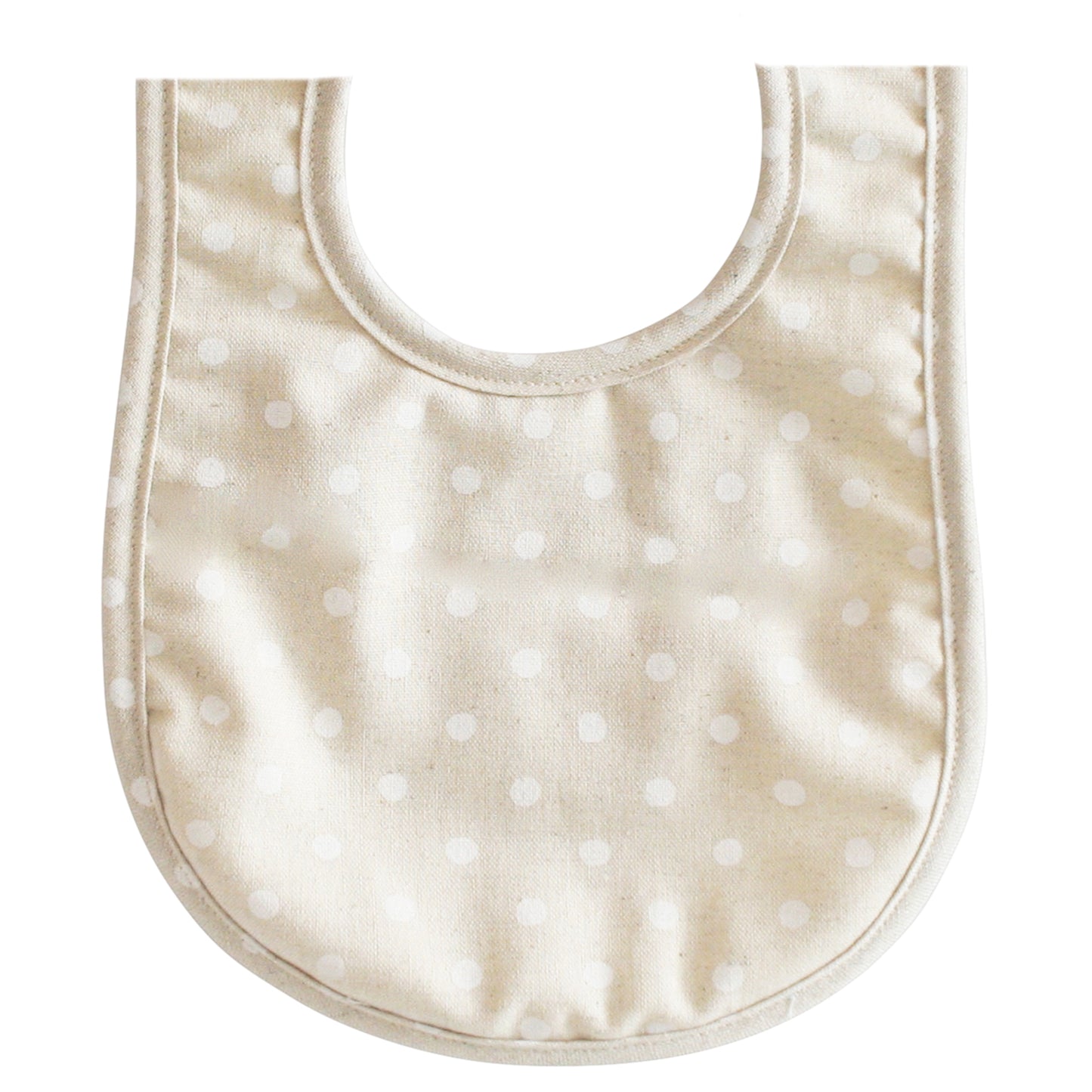 White linen baby bib with subtle white polka dot pattern and curved neckline.