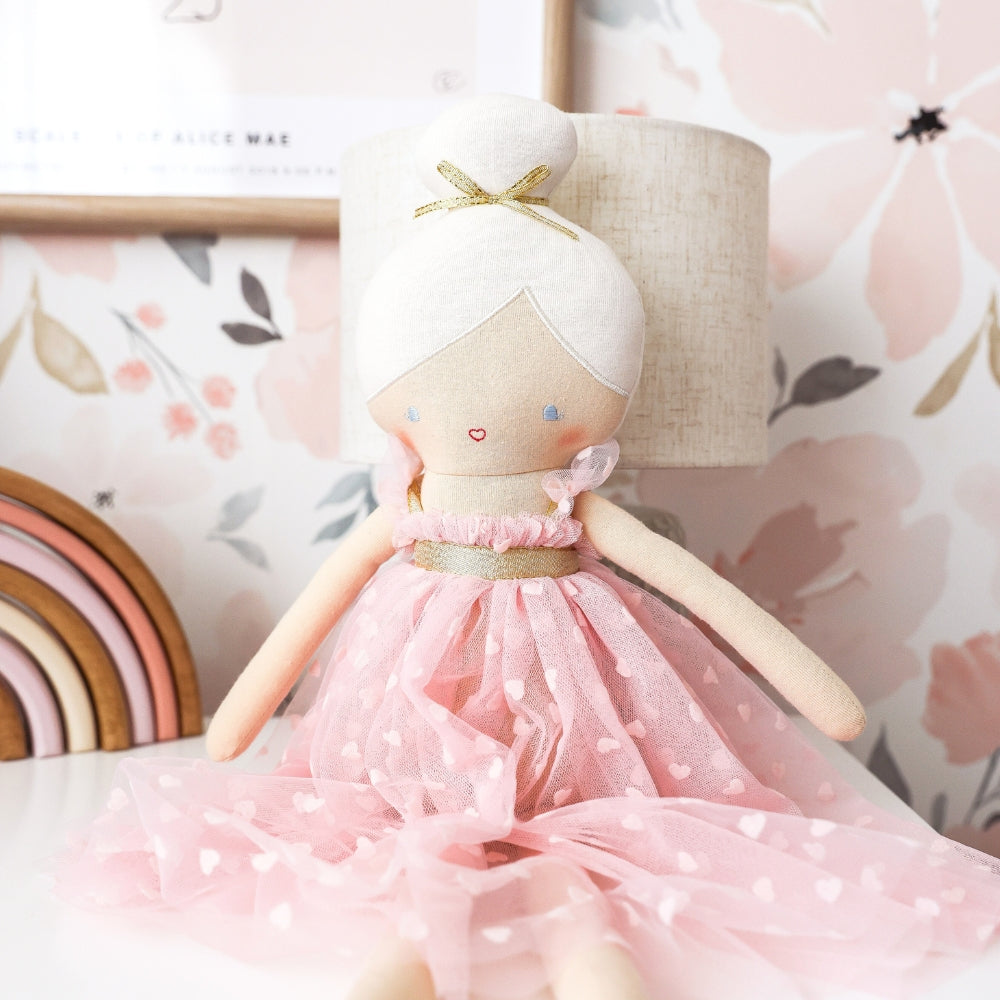 Soft fabric doll with white yarn hair tied in a bow, wearing a pale pink polka dot dress.