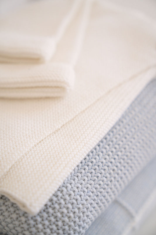Soft knit baby blankets in powder blue and cream, featuring mini moss stitch and scallop edge, perfect for newborns.
