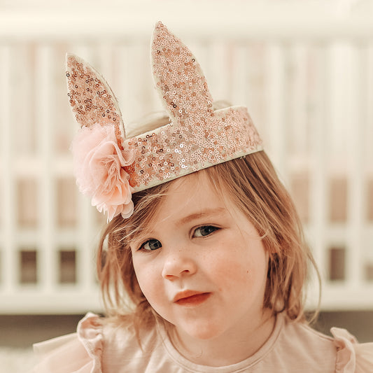 Cute child wearing a rose gold sequin bunny crown with a flower, perfect for playtime and dress-up.