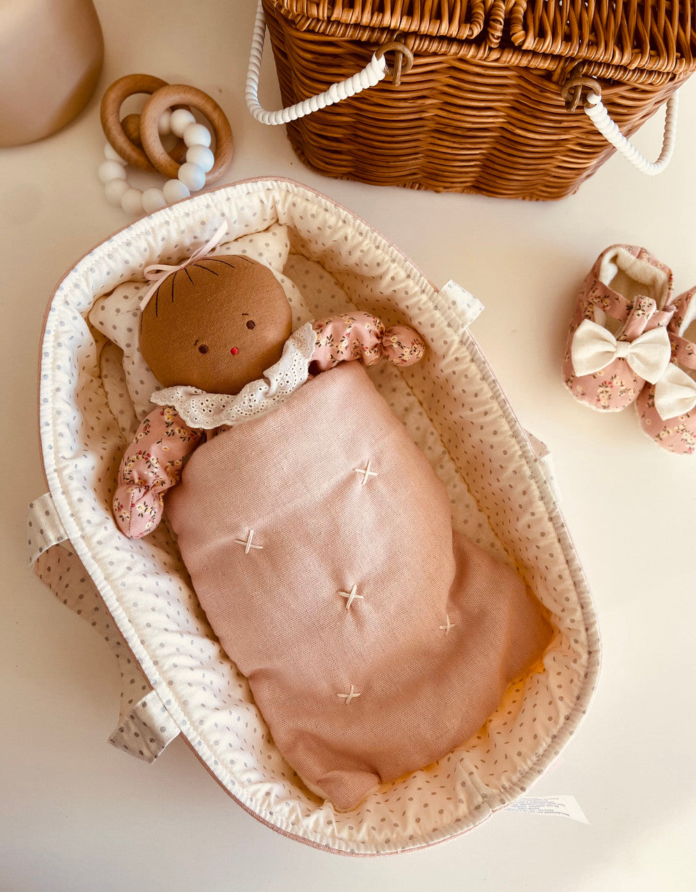 Alimrose Asleep Awake Baby Doll resting in a cozy cradle with a pink blanket and whimsical accessories.
