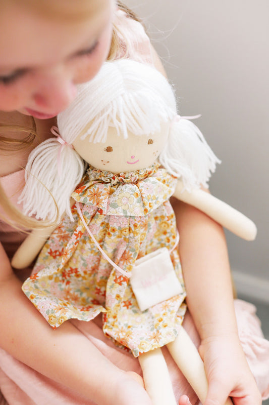 Eadie 48cm doll with floral dress and yarn hair, held by a girl, perfect for tea parties and imaginative play.