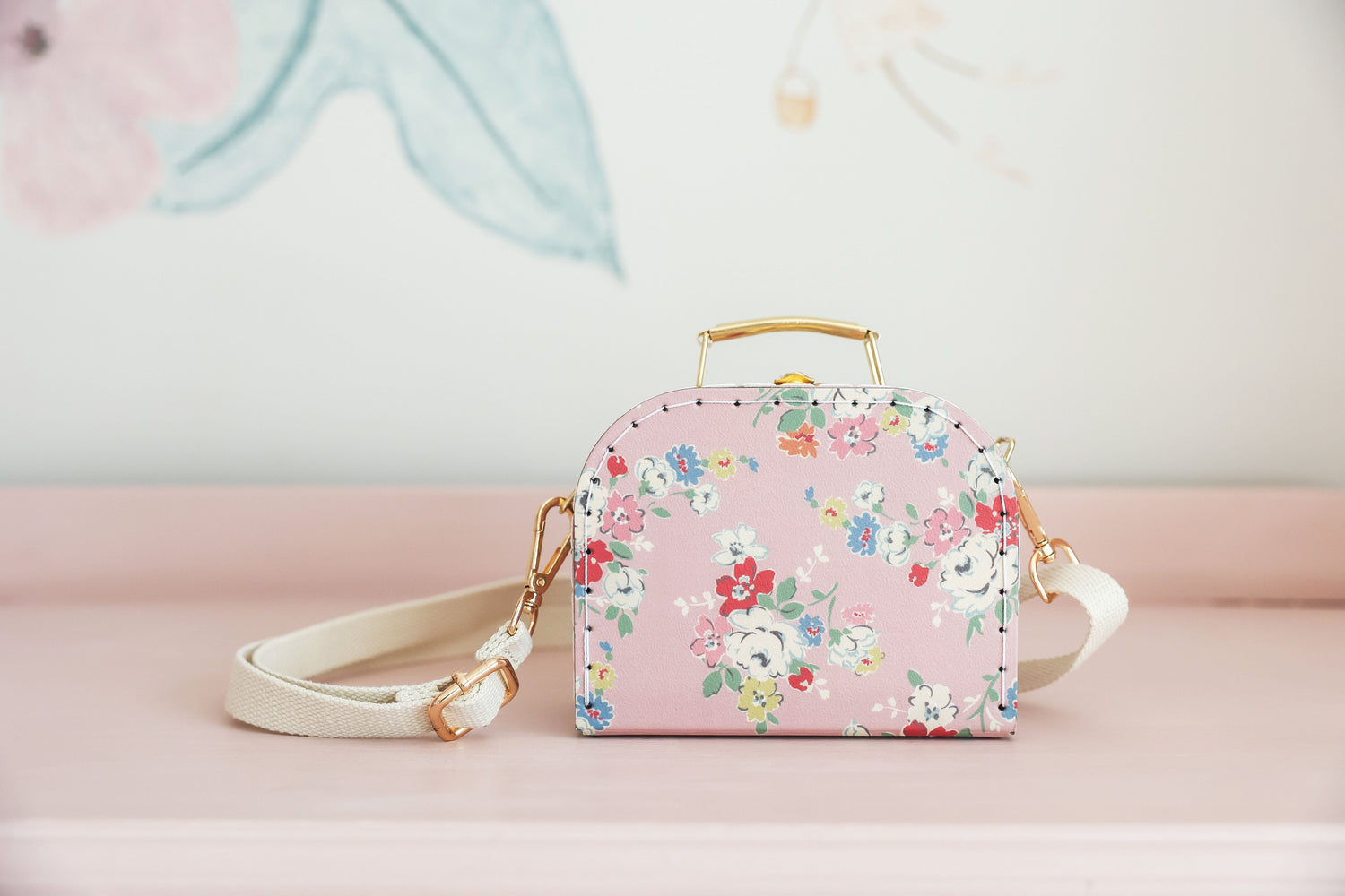 Small vintage rose crossbody bag with pastel floral print, gold-tone handle, and cream strap.