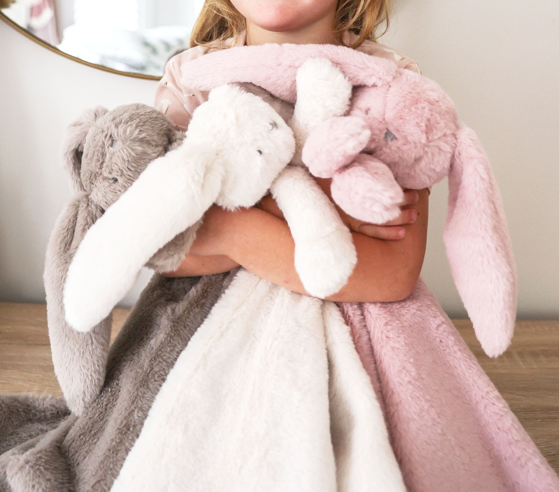 Plush ivory blanket with long-eared bunny lovey design held by child, soft textured fabric.