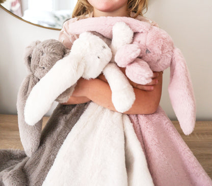 Plush ivory blanket with long-eared bunny lovey design held by child, soft textured fabric.