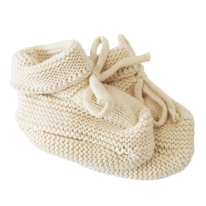 Soft cream-colored knit baby booties with fold-over cuffs and tie closures, sized 0-6 months.