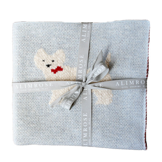 Folded blanket with a knitted dog toy and Alimrose ribbon on a white background