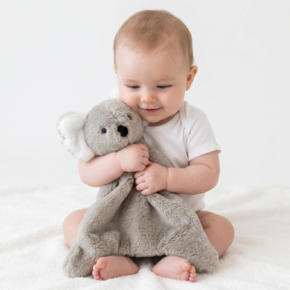 Baby cuddling soft gray koala plush security blanket with embroidered eyes and nose.