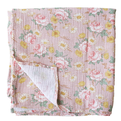 Light pink muslin swaddle with a floral pattern of roses and daisies, folded to show textured fabric and soft white.