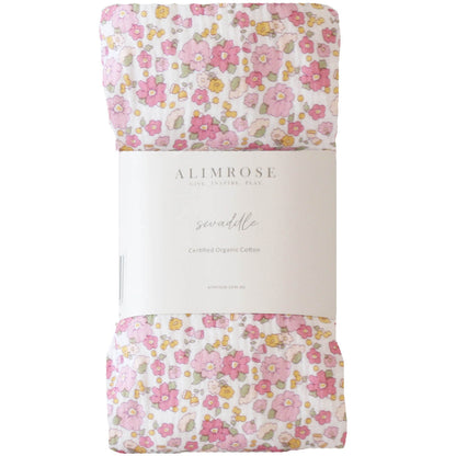 Soft muslin swaddle with pink, orange, and green rose garden floral pattern wrapped in white Alimrose label.