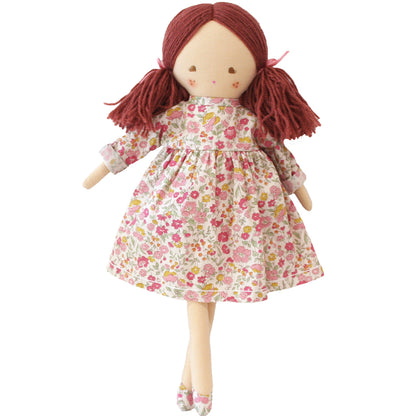 Cloth doll with red yarn hair in pigtails wearing floral pink and white dress and matching shoes.
