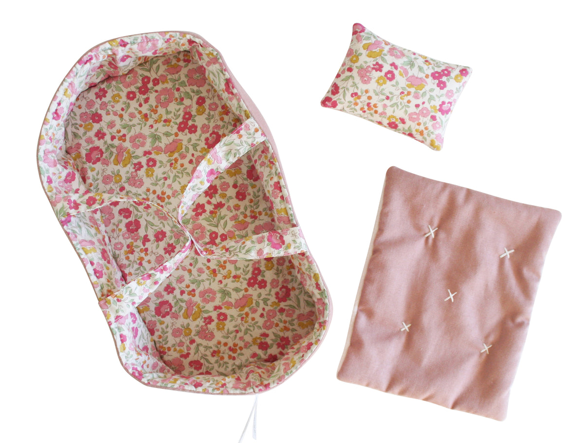 Floral pink doll carrier with matching pillow and soft pink blanket set.