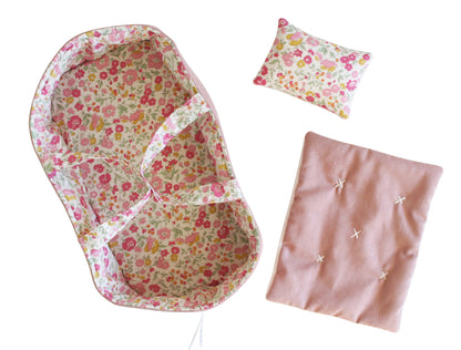 Floral pink doll carrier with matching pillow and soft pink blanket set.