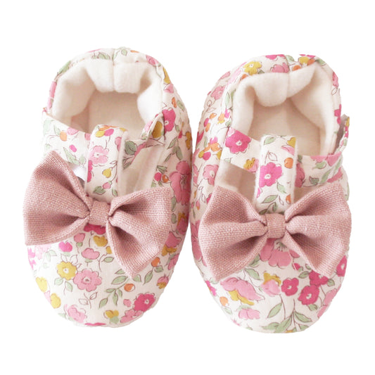 Soft fabric baby booties with pink velvet bows and a floral rose garden print in pink, yellow, and green.