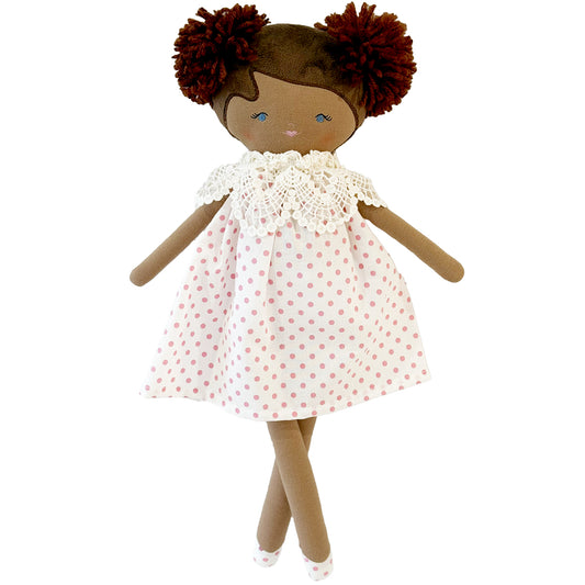 Cloth doll with brown skin, yarn hair in two burgundy pom-pom puffs, white dress with small red polka dots and crochet.