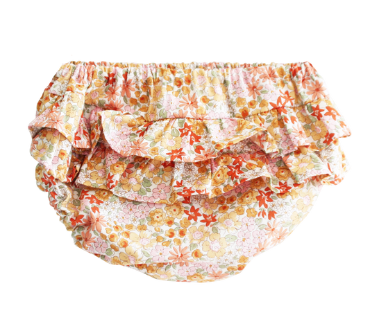 Baby bloomers in soft cotton with layered ruffles and a floral print in orange, pink, and yellow tones.