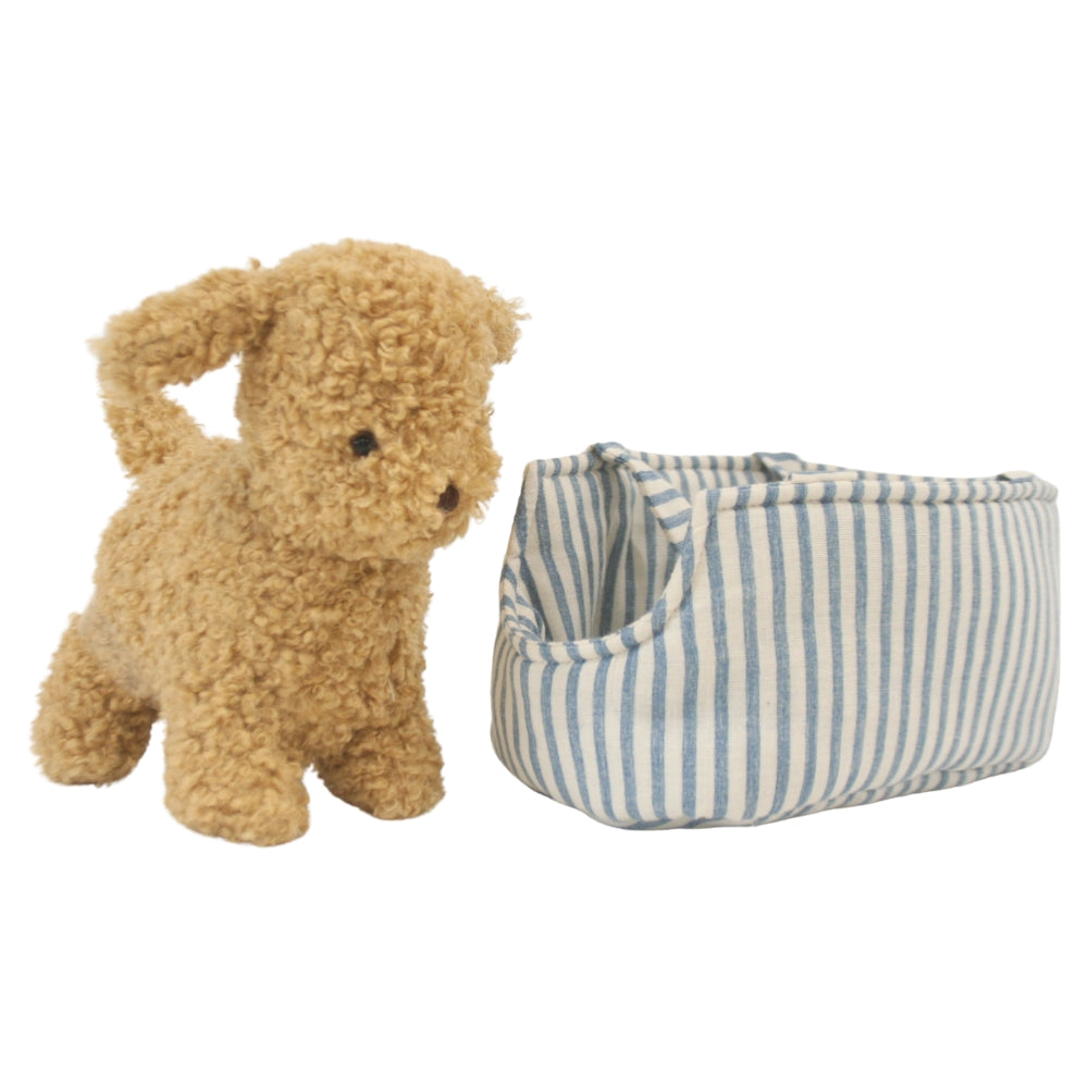 Soft tan plush puppy with floppy ears standing next to a blue and white striped fabric carrier with open top.