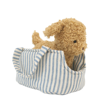 Small curly tan plush puppy sitting inside a soft blue and white striped fabric carrier with a handle.