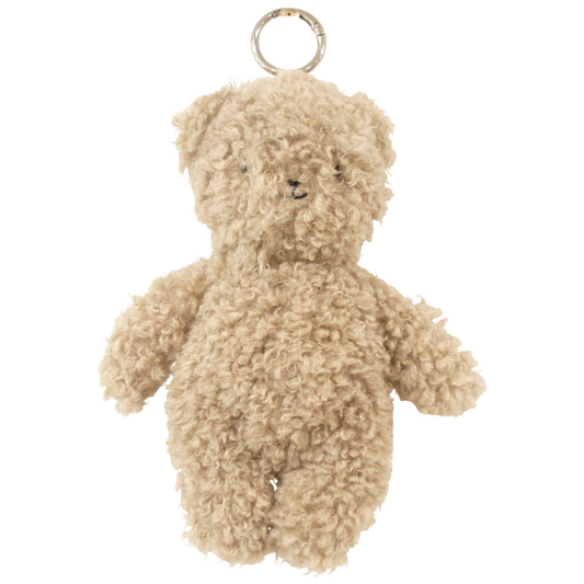 Small oatmeal-colored teddy bear bag charm with curly plush fur and silver keyring attached to the head.
