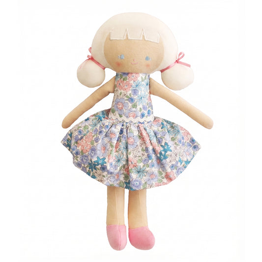 Soft fabric doll with pale skin, blonde hair tied with pink bows, wearing a blue floral dress and pink shoes.
