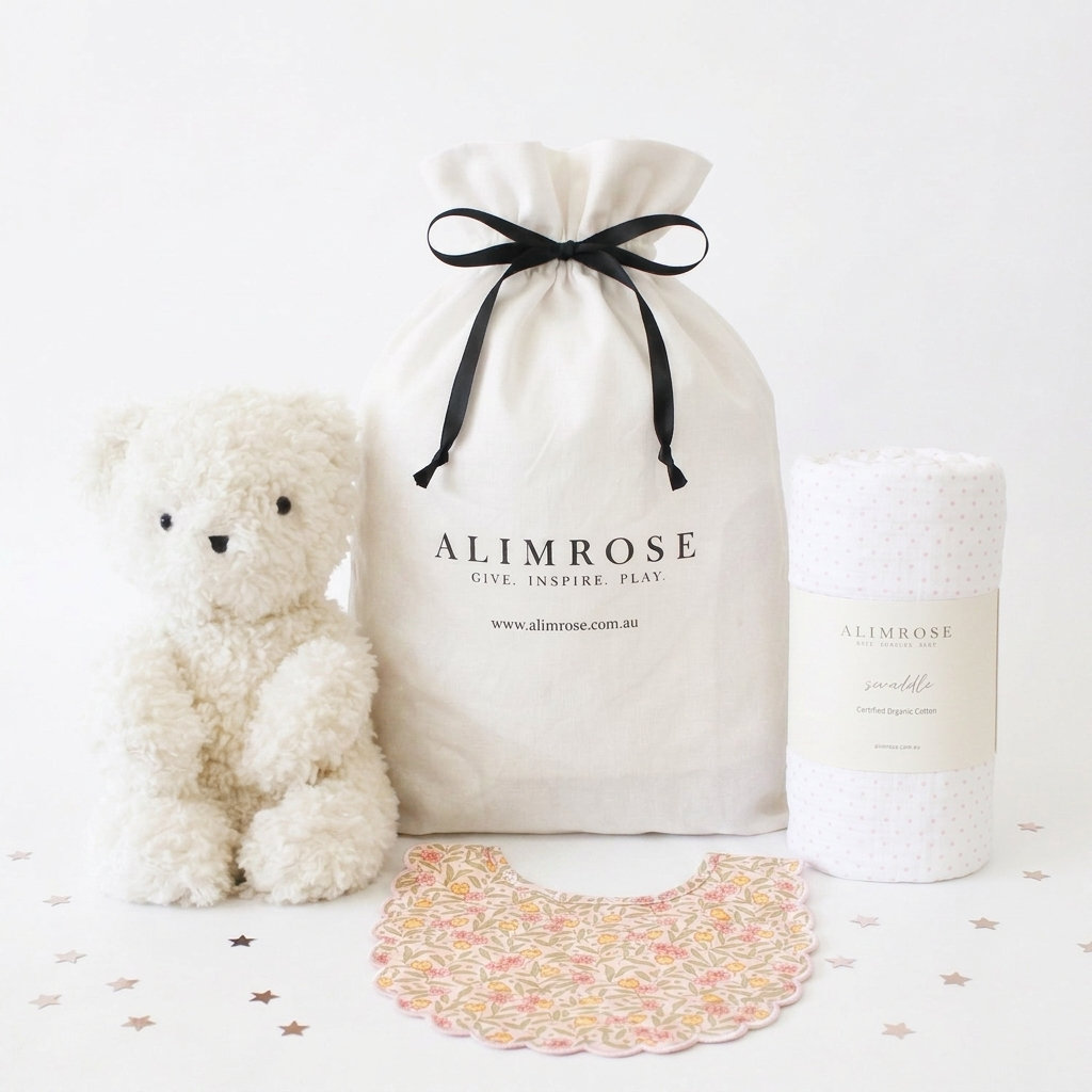 Soft white plush teddy bear, white fabric drawstring gift bag with black ribbon and logo, and rolled white textured baby.