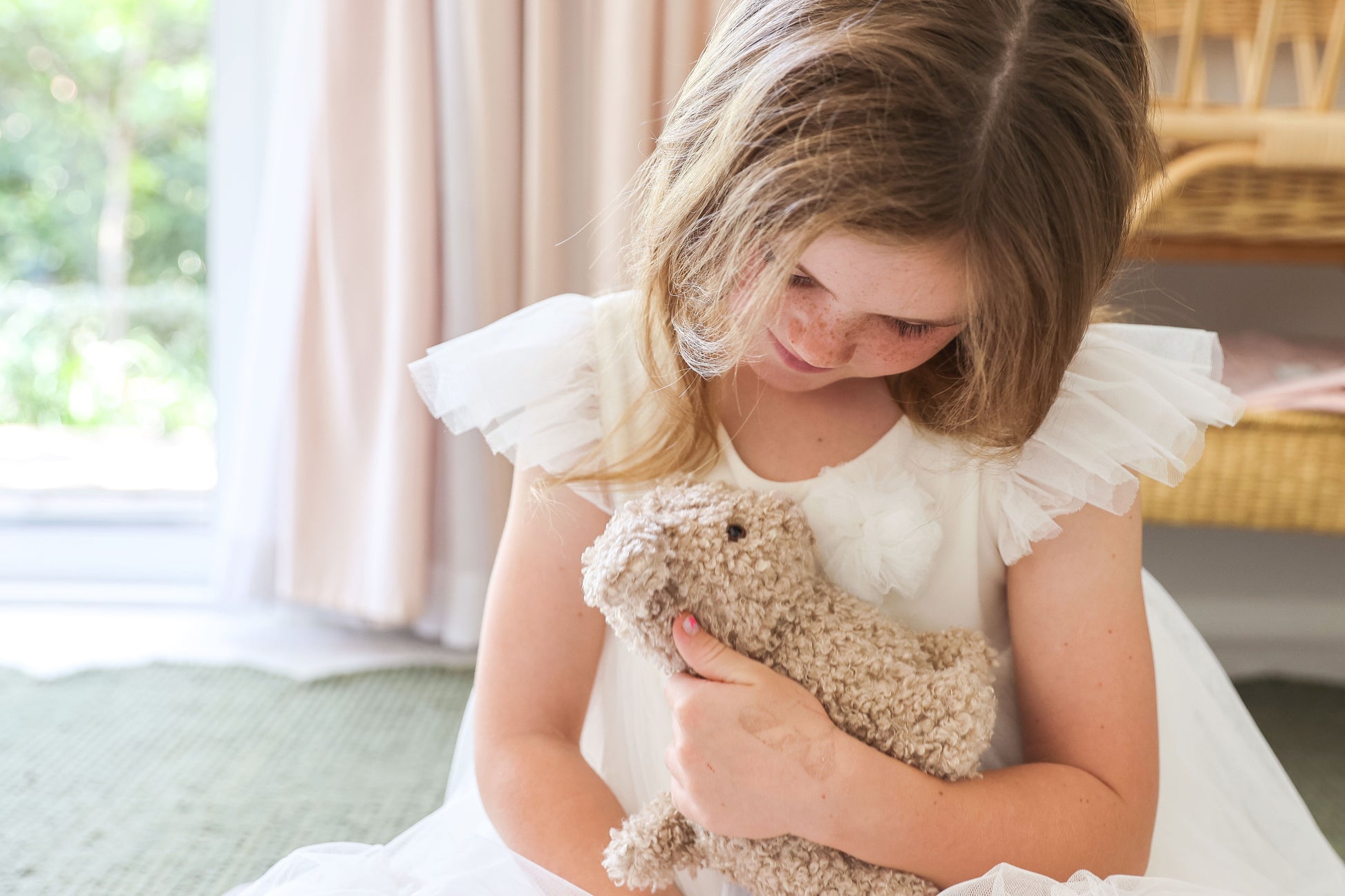 Child holding beige plush puppy with textured fur inside a soft, fabric carrier bag.