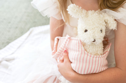 Soft white plush puppy named Marshmallow inside a pink and white striped fabric carrier held by a child wearing a white.
