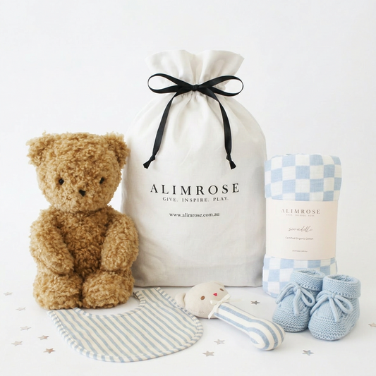 Blue and white deluxe gift hamper with teddy bear, striped bib, rattle, soft booties, and drawstring cotton bag.